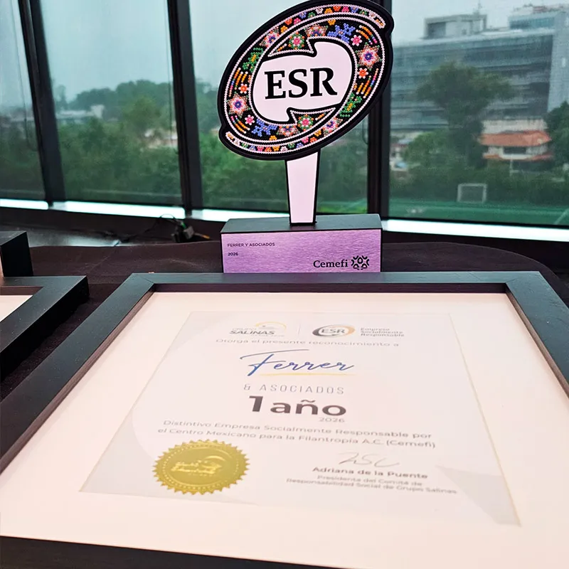 Trofeo del Distintivo ESR y reconocimiento enmarcado sobre un escritorio, con vista a la ciudad de fondo