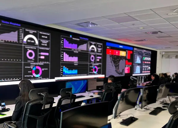 Vista panorámica del NOC con pantallas de dashboards de analítica y un mapa de México, varios analistas trabajando
